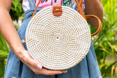 Stylich Eko dostu rattan çanta tropikal bir arka plan üzerinde kadın elle. Bali Adası.