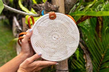 Stylich Eko dostu rattan çanta tropikal bir arka plan üzerinde kadın elle. Bali Adası.
