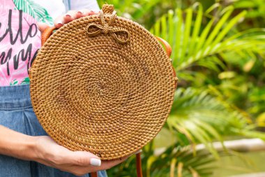 Stylich Eko dostu rattan çanta tropikal bir arka plan üzerinde kadın elle. Bali Adası.