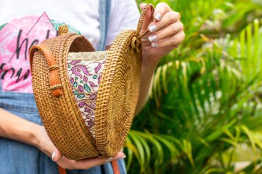 Stylich Eko dostu rattan çanta tropikal bir arka plan üzerinde kadın elle. Bali Adası.