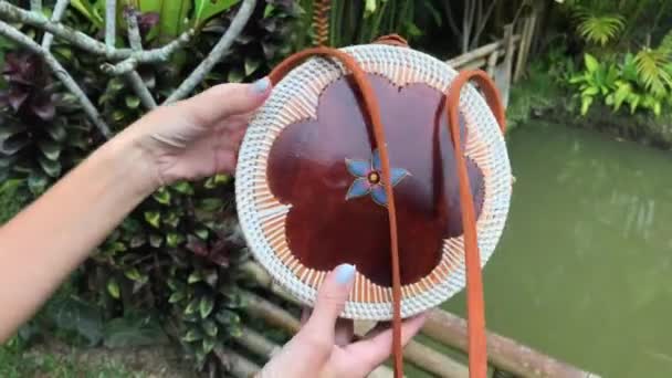 Nahaufnahme einer stilvollen, handgemachten Handtasche aus Rattan auf tropischem Hintergrund. bali-Insel. — Stockvideo