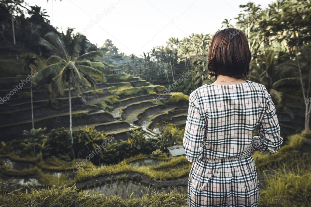 Young woman walking on rice field Tegalalang, Ubud, tropical island of Bali, Indonesia.