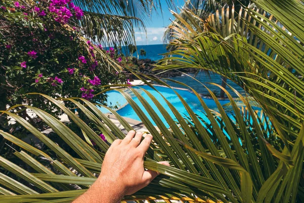 Man hand on a tropical swimming pool background. Dream island. Luxury resort. Bali island, Indonesia.