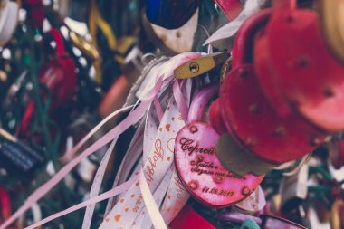 Bir korkuluk kilitleri köprüdeki üzerindeki aşk kilit bir bokeh arka plan oluşturmak için bulanık diğer kilit ile yakın çekim.