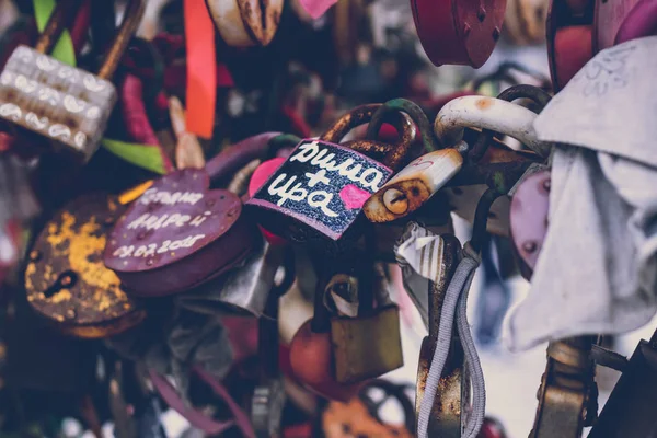 Närbild på en kärlek låsa på ett räcke på en Lås bro med andra lås suddig för att skapa en bokeh bakgrund. — Stockfoto