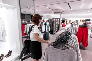 Alışveriş merkezinde kıyafet seçen genç bir kadın. Asya.