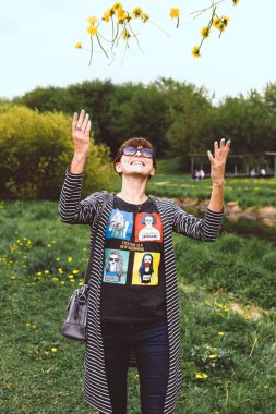 Güneşli yaz parkında sarı karahindiba ile genç güzel kadın.