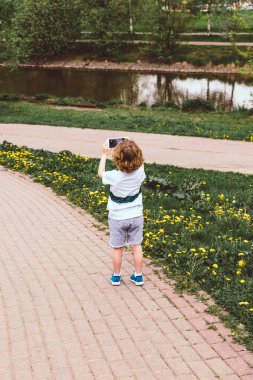 Bebek yeşil yaz parkında akıllı telefon kullanıyor.