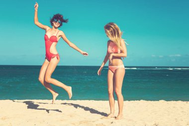 İki genç çekici kadın sahilde atlama ve Bali adasında tatil sırasında eğlenmek.