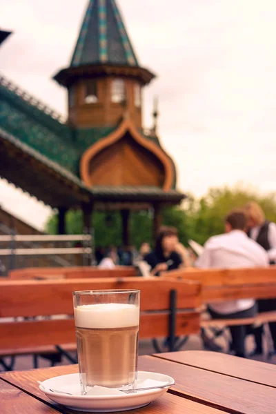 Egy pohár forró ízű latte egy kanál egy fából készült asztal. — Stock Fotó