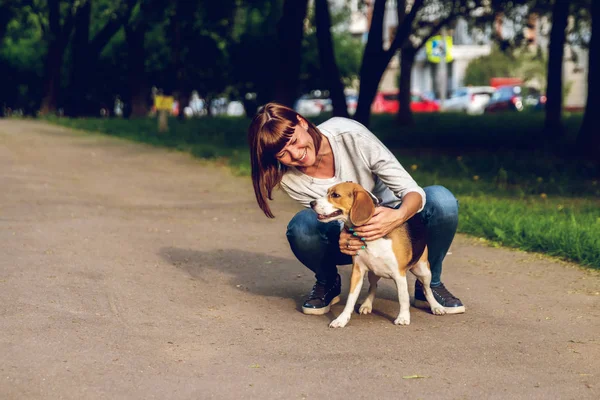 Chica sosteniendo un perro en sus brazos en el fondo de la naturaleza en la hora de verano. Estilo de vida foto . —  Fotos de Stock