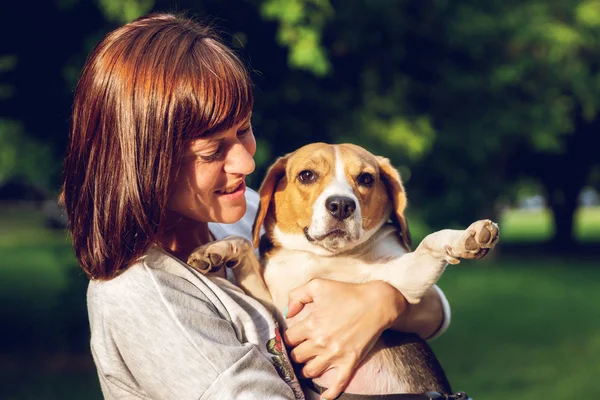 Menina segurando um cão em seus braços no fundo da natureza na hora de verão. Estilo de vida foto . — Fotografia de Stock