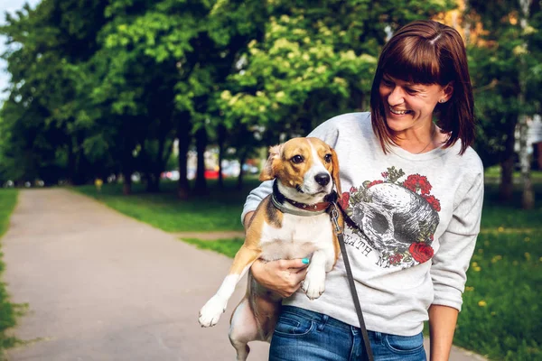 Chica sosteniendo un perro en sus brazos en el fondo de la naturaleza en la hora de verano. Estilo de vida foto . —  Fotos de Stock