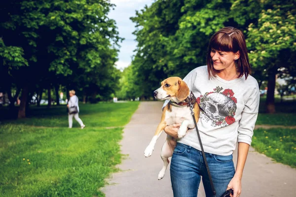 Chica sosteniendo un perro en sus brazos en el fondo de la naturaleza en la hora de verano. Estilo de vida foto . —  Fotos de Stock