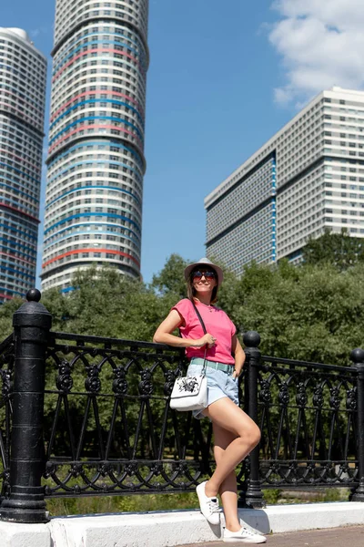 Frau mit Hut posiert an der Brücke im Stadtpark. — Stockfoto