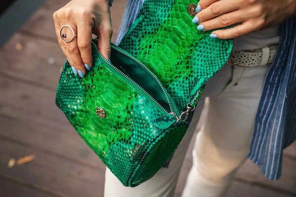 Stylish woman with snakeskin handbag outdoors.