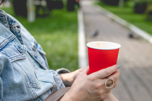 Young woman holding a red coffee paper cup, lifestyle summer shot.