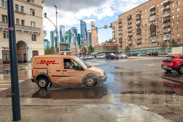 MOSKOU, RUSSIE - 27 JULI 2020: De DHL auto rijdt door plassen na een regenbui. — Stockfoto
