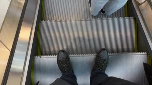 사람이 에스컬레이터 위에 서 있다. 계단. — 비디오