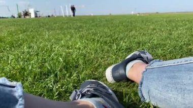 Spor ayakkabılı kadın ayakları, güneşli yeşil çimlerin üzerinde ayakkabılar, yakın..