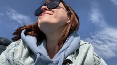 Güneş gözlüklü genç bir kadın. Yakın plan, güzel bir gökyüzü arkaplanı..