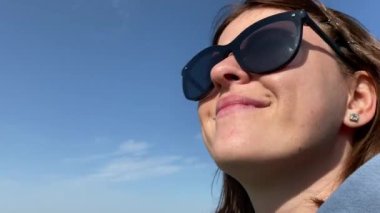 Güneş gözlüklü genç bir kadın. Yakın plan, güzel bir gökyüzü arkaplanı..