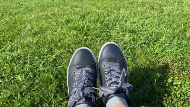 Spor ayakkabılı kadın ayakları, güneşli yeşil çimlerin üzerinde ayakkabılar, yakın.. — Stok video