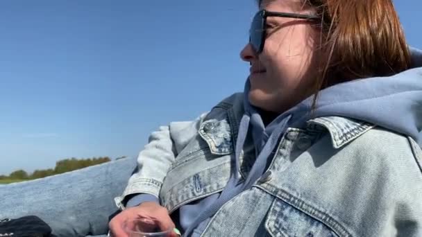 젊은 여성이 자연의 배경 위에 플라스틱 와인 잔을 놓고 그림을 그리고 있습니다. 생활 방식 영상. — 비디오