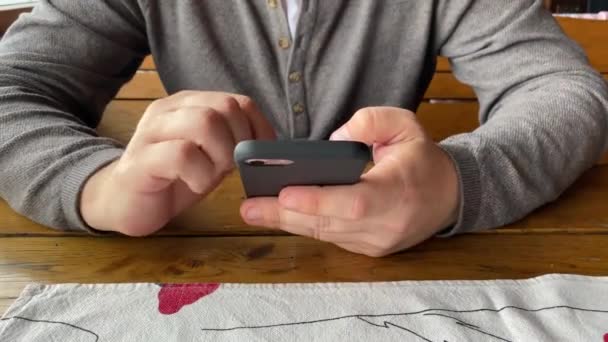 Primer plano de vídeo del hombre usando el teléfono inteligente sentado en la cafetería. Primer plano de las manos. — Vídeo de stock