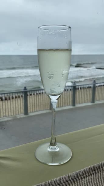 A glass of champagne on seashore background. White sparkling wine. — Stock Video