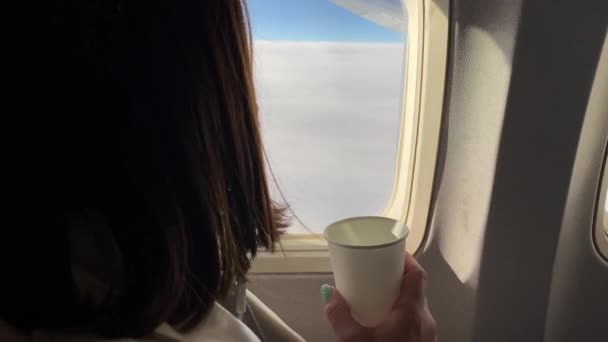Young woman drinks water during the flight in aircraft and looks into window. — Stock Footage Young woman drinks water during the flight in aircraft and looks into window. Stock Footage