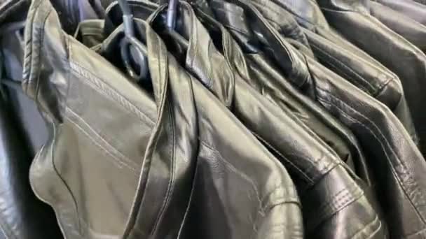 Olcsó bőrdzsekik a boltban. Akasztják a kabátokat.. — Stock videók