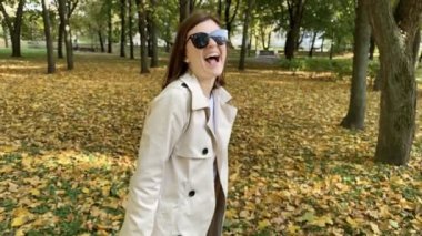 Sonbahar parkında gülen bir kadının komik yavaş çekim görüntüleri. Sarı sonbahar parkı.