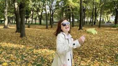 Sonbahar parkında gülen bir kadının komik yavaş çekim görüntüleri. Sarı sonbahar parkı.