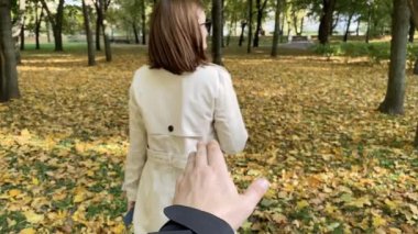 Genç bir kadının romantik sonbahar görüntüsü kocasına sonbahar yaprağı veriyor. Yavaş çekim videosu.