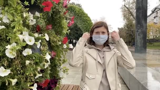 Νεαρή γυναίκα βγάζει τη μάσκα του ιατροδικαστή στο φθινοπωρινό πάρκο. Έννοια ελευθερίας. — Αρχείο Βίντεο