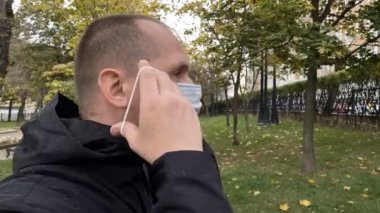 Adam parkta tıbbi koronavirüs maskesi takıyor. Yavaş çekim görüntüleri.