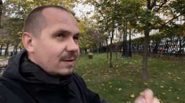 Genç adam parktaki tıbbi koronavirüs maskesini çıkarıyor. Yavaş çekim.