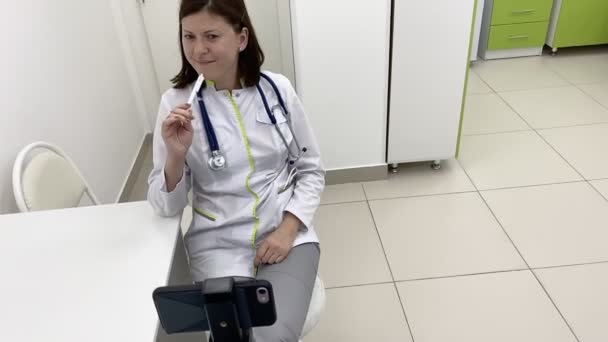 Молодой врач дает онлайн консультации с помощью смартфона. — стоковое видео
