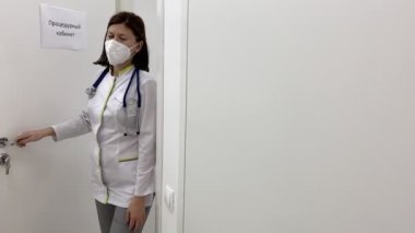 Tıbbi maskeli kadın doktor kabinesini klinikte bırakıyor. Yavaş çekim görüntüleri.