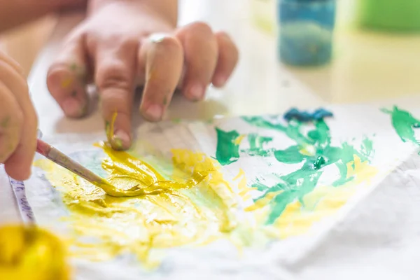Un bambino piccolo disegna vernici su un tavolo . — Foto Stock