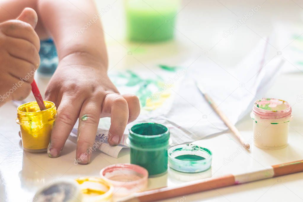 A small child draws paints on a table.