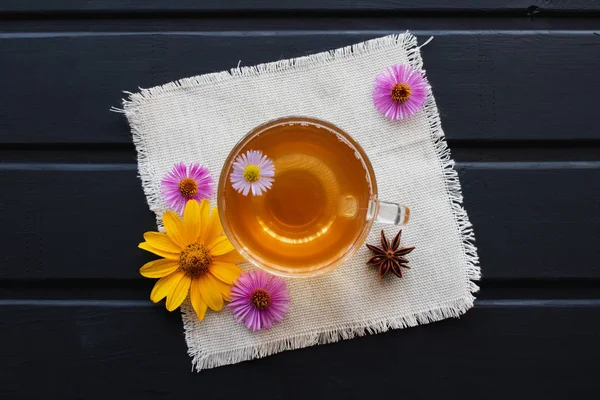 Blomma te i ett genomskinligt glas cup på tabellen svart. Helande te. — Stockfoto