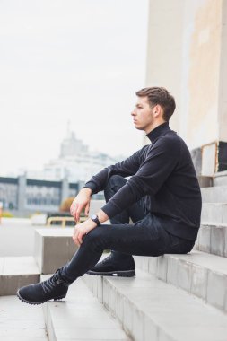 Genç adam belgili tanımlık merdiven üstünde oturuyor