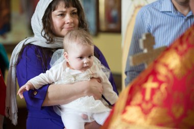  Bir çocuğun vaftizi. Anne, vaftiz ayini sırasında çocuğu elinde tutar. Dinini kabul et.