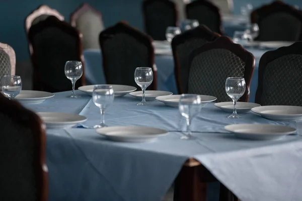 Table in the restaurant with empty plates and glass goblets.Empty table in the restaurant