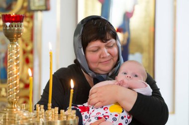 Beyaz Rusya, Gomel, 6 Mayıs 2018. Kilise Volotovo. Yeni doğan bir çocuğun vaftiz. Bir kilisenin sunak yılında bir eski Rus büyükannesiyle bir fularlı