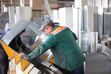 Beyaz Rusya, Gomel, 25 Nisan 2018. Fabrika havalandırma boruları üretimi için. İki işçi fabrikada atölyede metal havalandırma boruları olun