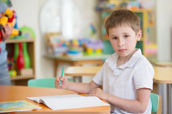 ノートとペンを持つクラスのテーブルで男児 — ストック写真