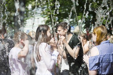 Beyaz Rusya, Gomel şehir, 09 Mayıs 2018. Zafer bayramı kutlaması. Park.Belarus, Gomel şehir 09 Mayıs 2018. Zafer bayramı kutlaması. Park. Oğlan ve kız su jetleri altında. Havuza yüzmek. Çift yağmurda
